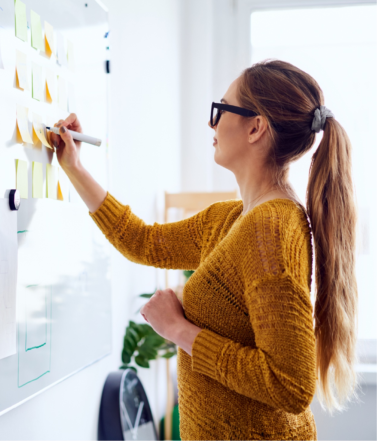 Une femme écrivant sur un tableau blanc pendant une séance de brainstorming